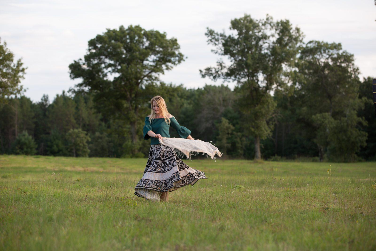 lady in field with shawl spinning