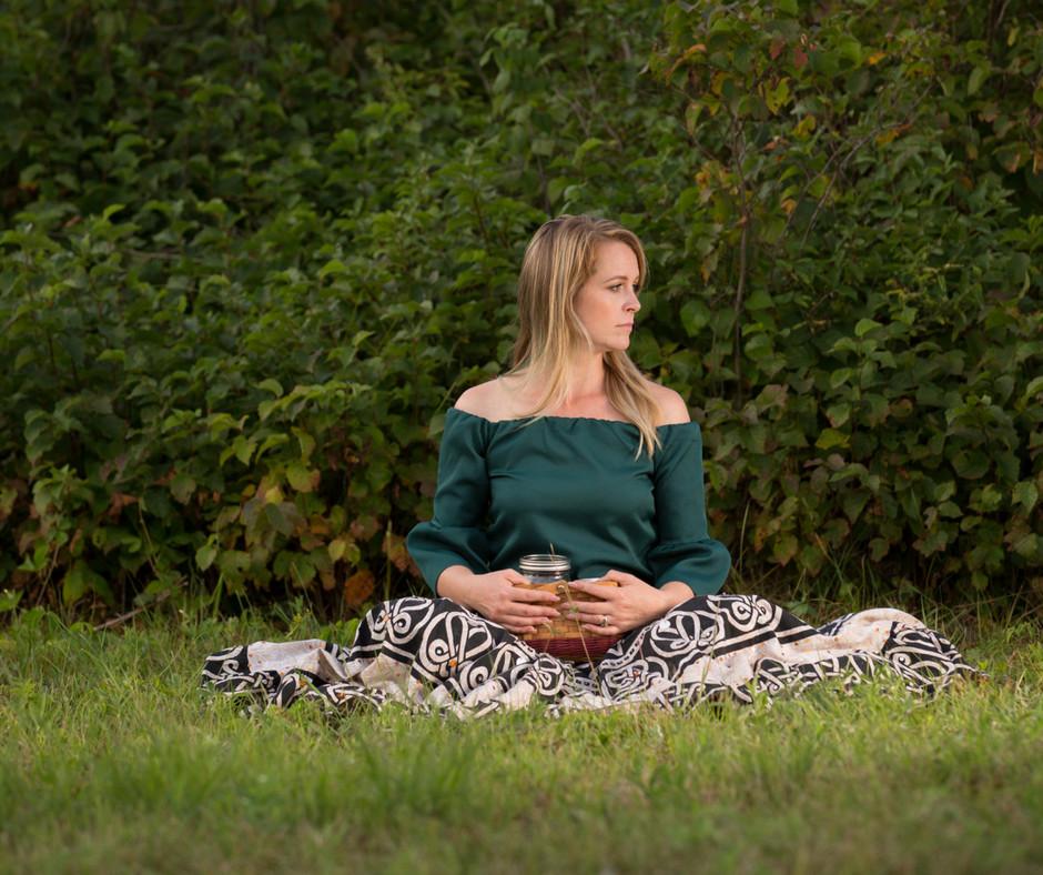 erin sitting on grass with a basket in her lap, looking into the distance