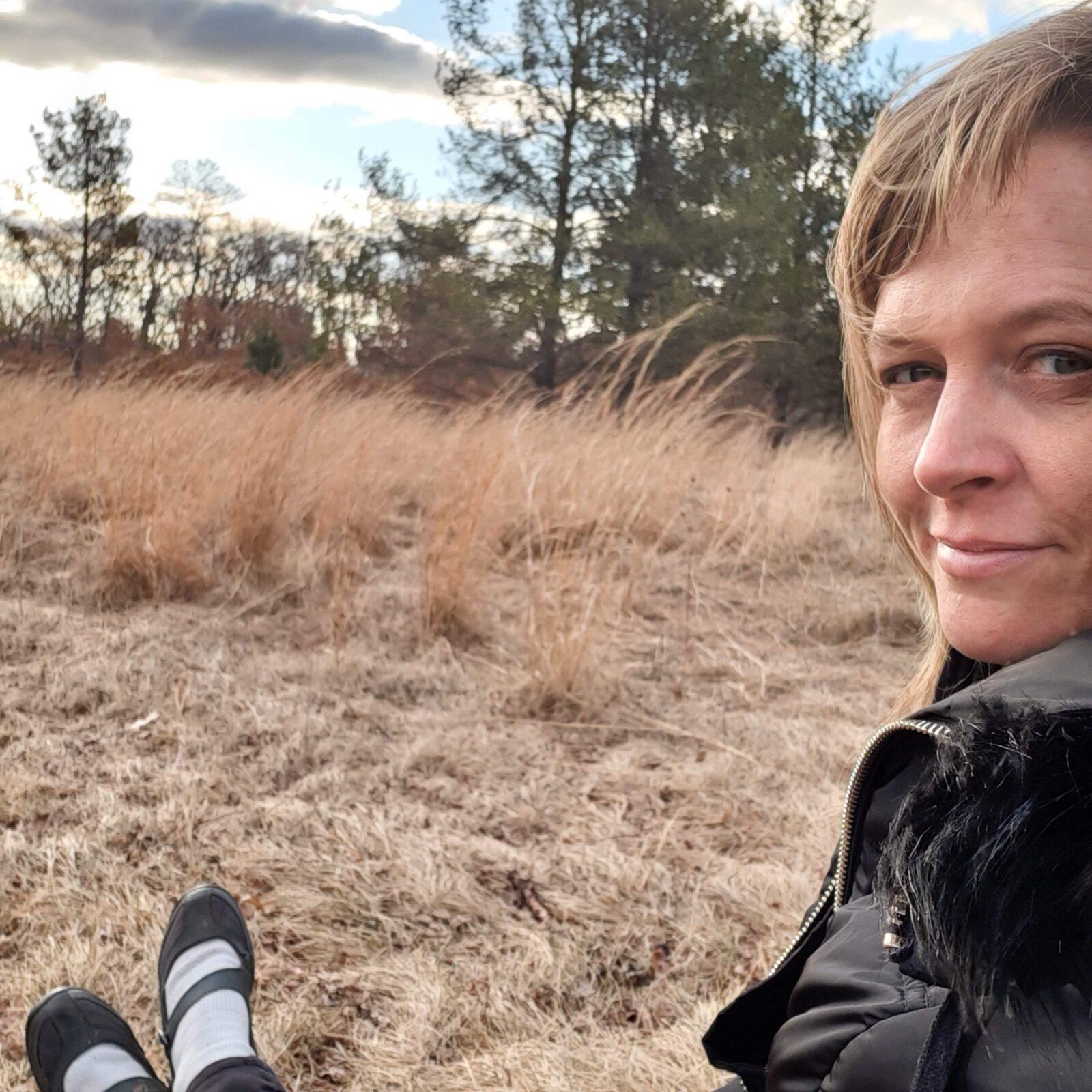 Erin sitting in the brown grass