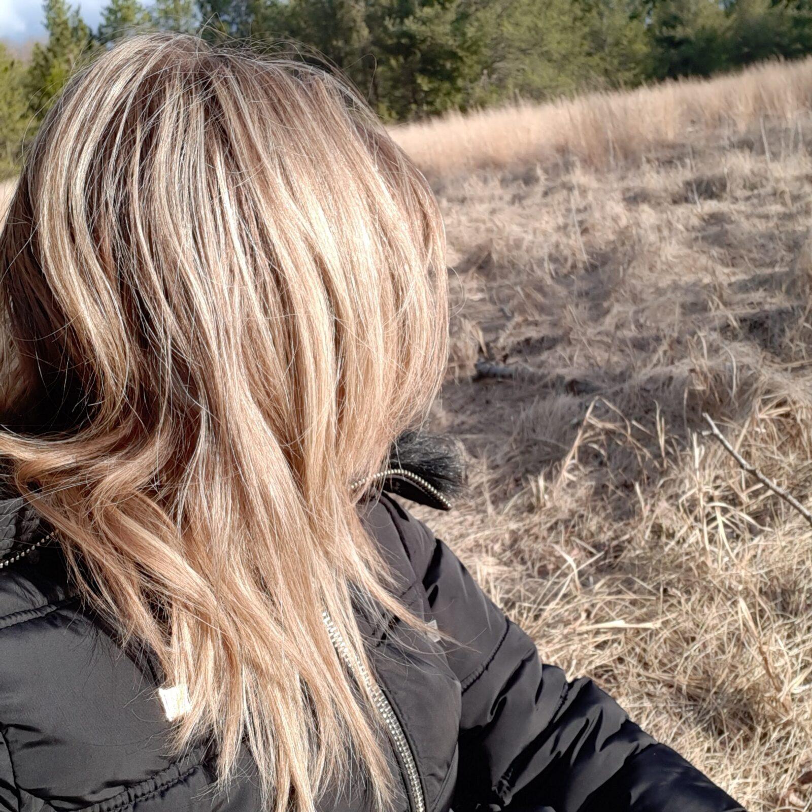 Erin's turned head with blond hair and blond looking grass in the background