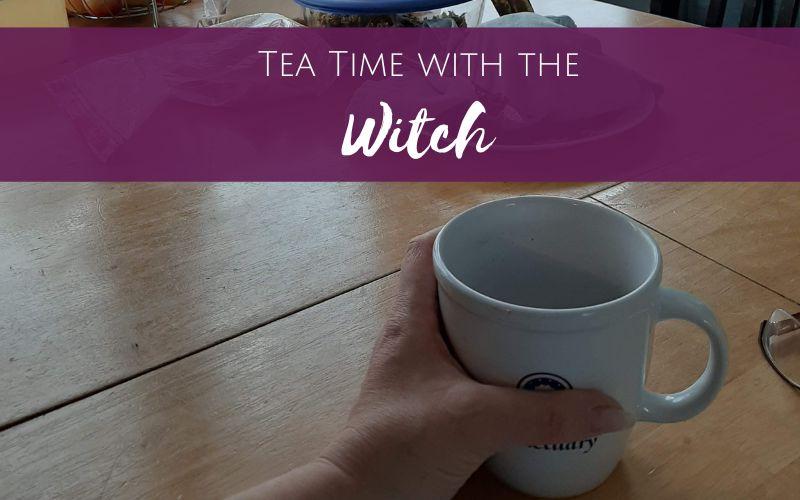 hand on a tea mug, title tea time with the witch