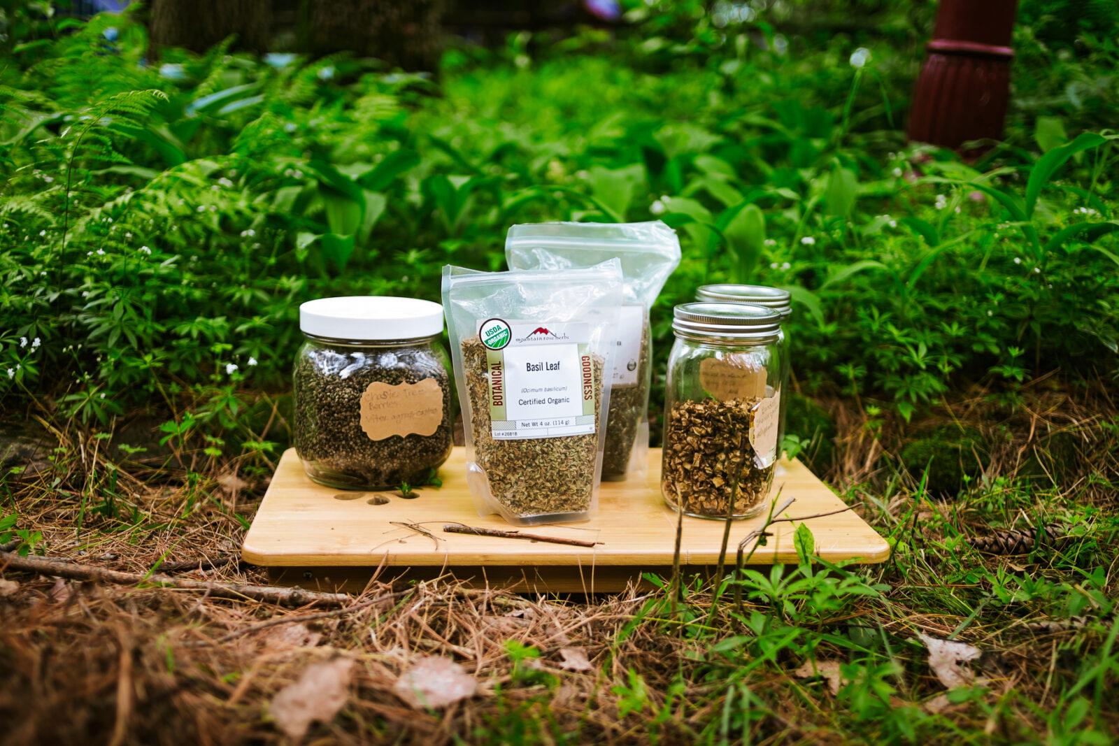 herbs in jars and bags on a tray. The tray is on the ground. 